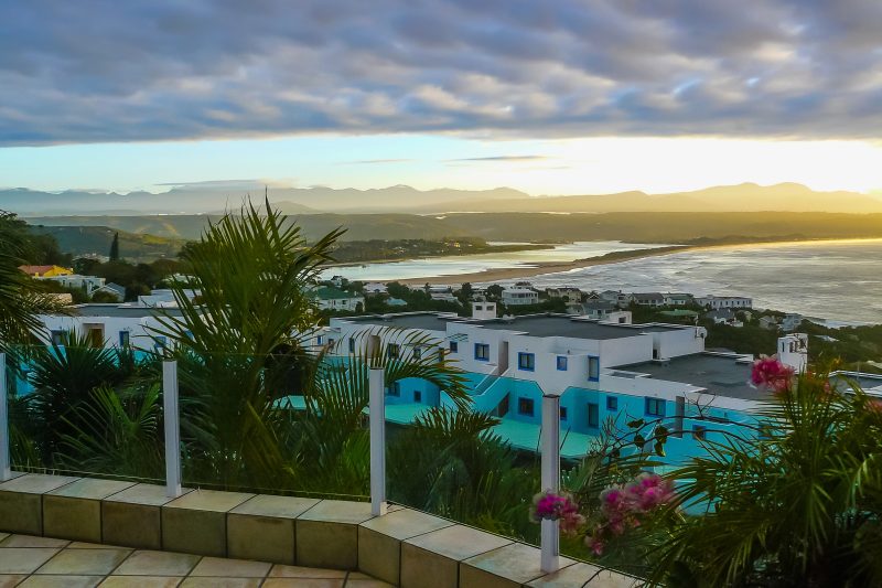 Blick über Hoteldächer und Palmen auf die Bucht von Mossel Bay am Abend